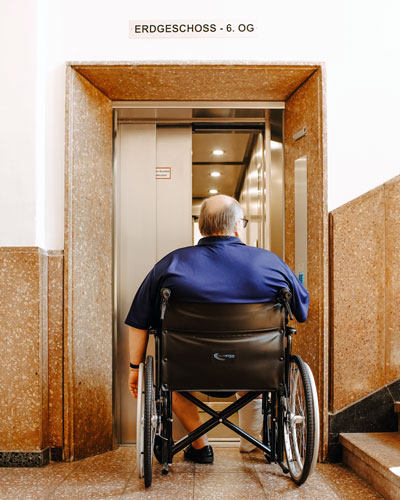 Ein Mann im Rollstuhl bei der Einfahrt in einen Aufzug im Karl Bröger Haus