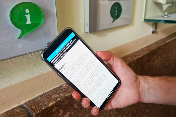 Über eine grüne Info-Sprechblase an der Wand werden mittels Smartphone und Speechcode Informationen einfach vermittelt