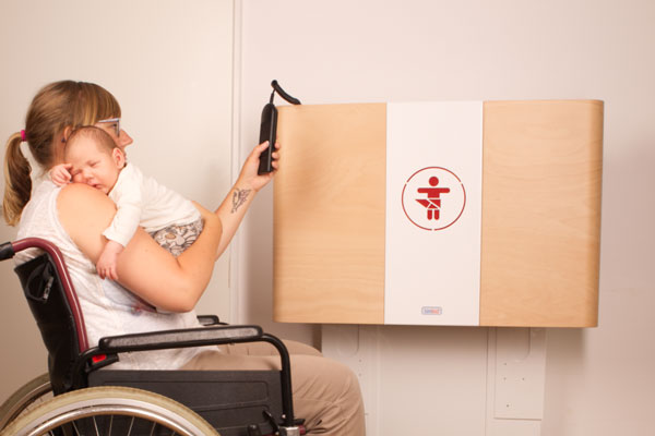 Eine Mutter im Rollstuhl öffnet einen der elektrisch höhenverstellbaren Wickeltische im Karl Bröger Haus